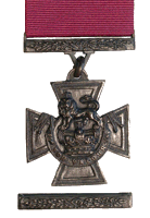 A bronze cross pattée bearing the crown of Saint Edward surmounted by a lion with the inscription FOR VALOUR. A crimson ribbon is attached