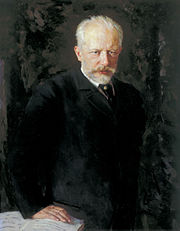 A middle-aged man with grey hair and a beard, wearing a dark suit and staring intently at the viewer.