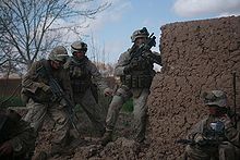 Soldiers beside a mud wall