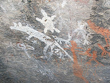 gray stone wall with white and orange primitive drawings