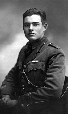 young man dressed in a uniform sitting on a chair facing the camera